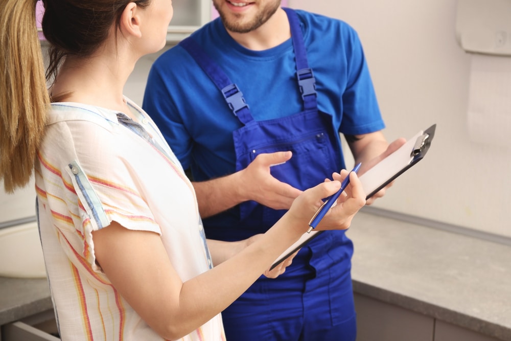 Professional,Plumber,In,Uniform,Talking,To,Client,Indoors